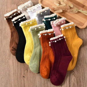 Set of 11 colors vintage ribbed cotton socks with lace trim and pearls on wooden floor