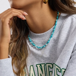 Detailed close-up of a blue turquoise beaded stainless steel necklace on a model's neck