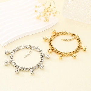 Detailed macro view of gold and silver bell charm bracelets with Cuban links