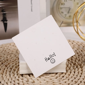White earring display cards with smiling face and Hello text on a straw mat background