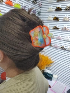 Detail view of a large butterfly hair claw clip with colorful marble pattern on long hair