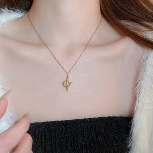 Dettaglio di una collana a croce dorata con cristalli scintillanti sulla clavicola