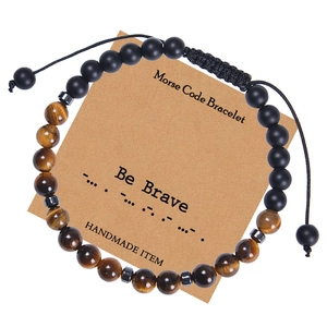Détail du bracelet code Morse avec perles œil de tigre et message 'Be Brave' sur carte