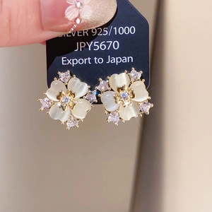 Detail of white cat eye stone flower earrings with 925 silver needles and gold edges