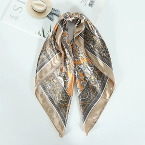 Golden paisley print square silk scarf for women elegantly folded on white background