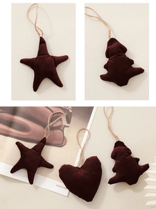 Dettaglio di decorazioni natalizie in velluto bordeaux scuro a forma di stella, cuore e dino