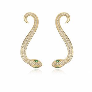 Macro detail of gold snake stud earrings with white zircon pavé and green gemstone eyes