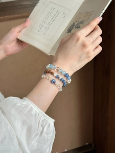 Nahaufnahme von eleganten Kristall- und Holzperlenarmbändern an einem Handgelenk mit Buch