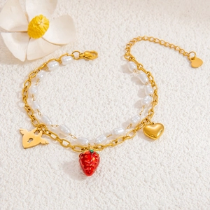Detail of double-layer bracelet with gold chain, white pearls and strawberry charms