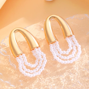 Close-up of elegant gold U-shaped earrings with triple-layer white pearl tassels