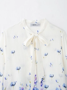 Detail of floral print blouse showing bow tie neckline and elegant blue flower patterns