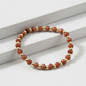 Detail of 4mm faceted amazonite beads and gold-plated metal spacers on a stone background