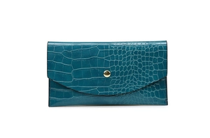Detailed view of teal crocodile embossed envelope wallet with a gold circular clasp