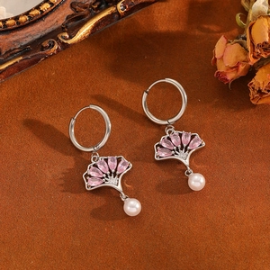 Gros plan détaillé de boucles d'oreilles en argent avec pierres roses et perles blanches