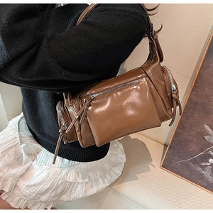 Détail du sac vintage marron brillant avec plusieurs poches zippées et tirettes en cuir