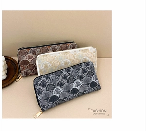 Close-up of three long wallets in brown, cream, and grey with embroidered fan patterns