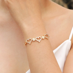 Sparkling gold heart bracelet with zircon stones worn on a female wrist in warm light