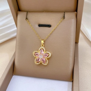 Close-up of pink zircon flower pendant in a jewelry box with a gold chain necklace