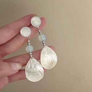 Close-up of shell teardrop earrings with silver metal beads and white resin pearls