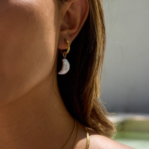 Close-up of 18K gold textured hoop earrings with dangling white baroque pearls on model