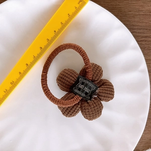 Close-up of brown corduroy flower hair tie with handmade label and measuring ruler