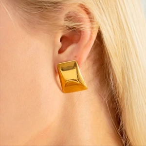 Close-up of a large gold polished trapezoid earring worn by a model for size