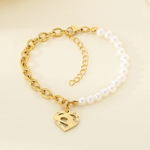 Detailed view of gold chain link bracelet with white pearl and hollow heart pendant