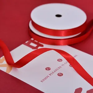Glossy red satin ribbon roll for gift wrapping and wedding decor on white card