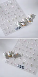 Macro shot of 3D embossed floral nail stickers featuring white flowers and grid patterns