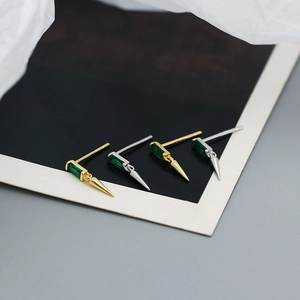 Detailed macro view of S925 silver stud earrings with green zircon and metal cone pendant