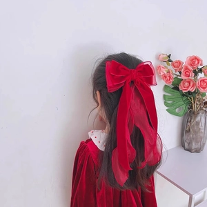 Detailed back view of a large burgundy velvet bow hair clip with ribbons on a girl