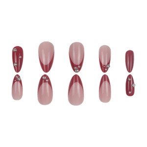 French almond press-on nails in deep red and nude pink with silver bead accents