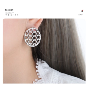 Close-up of vintage hollow mesh disc earrings in silver finish worn by a model
