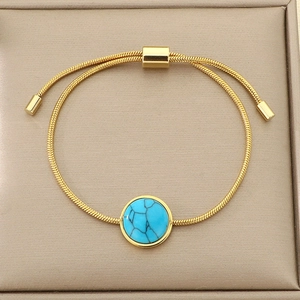 Détail du bracelet chaîne serpent dorée ajustable avec pierre turquoise sur socle beige