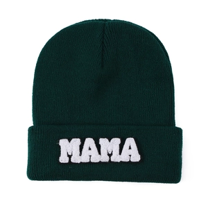 Close-up of MAMA towel embroidery on dark green knit beanie hat for winter