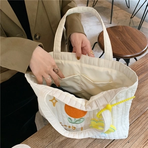 Detailed interior of quilted tote bag with dual inner pockets and orange embroidery