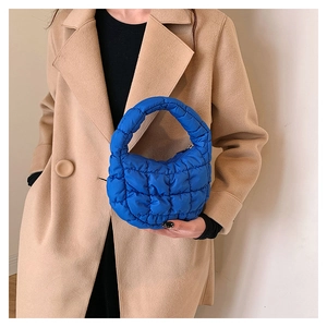 Detail view of blue quilted puffy cloud handbag with a glossy nylon texture on shoulder
