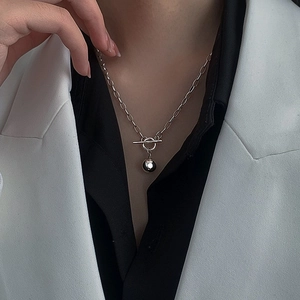 Detail of silver OT buckle chain necklace with polished sphere pendant on a model
