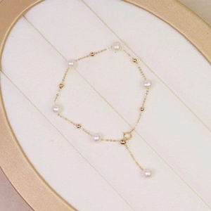 Detailed macro view of a gold chain pearl bracelet with adjustable extension on a tray