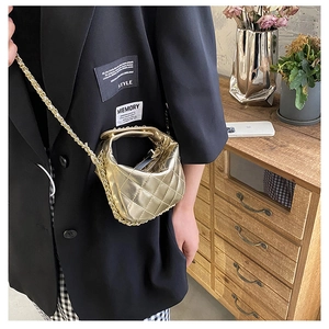 Detail of a mini gold crossbody bag with diamond quilting and metallic chain strap
