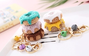 Close-up of handmade crochet donut keychains with colorful bells on a ceramic tray