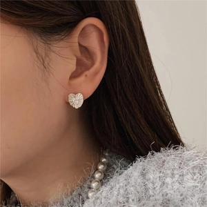 Detail of 925 sterling silver heart stud earrings with radiant texture and zircon on ear