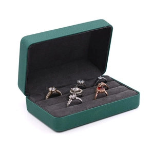 Detail view of open dark green velvet jewelry box with rings in storage slots