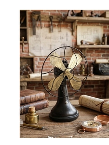 Detail of vintage industrial metal desk fan with rustic brass blades on a wooden desk