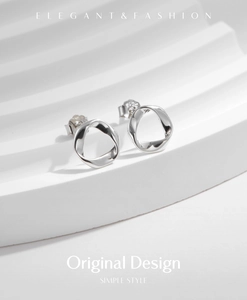 Macro view of minimalist silver S925 wavy geometric stud earrings on a white prop