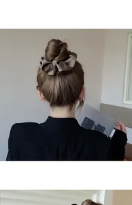 Detail of elegant chocolate brown satin scrunchie styled on a classic bun hairstyle
