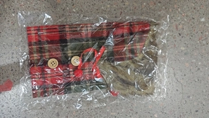 Detail of red and green plaid wine bottle cover with faux fur trim and wood buttons
