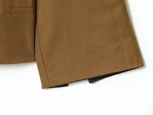 Close-up of brown twill fabric with detailed stitching and striped lining detail