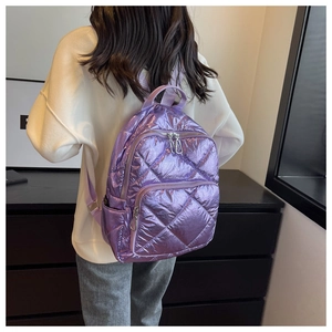 Detailaufnahme eines lila gesteppten Rucksacks mit Metallic-Effekt und Trägern am Model