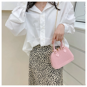 Pink woven texture jelly shell bag with gold chain strap shown on a female model